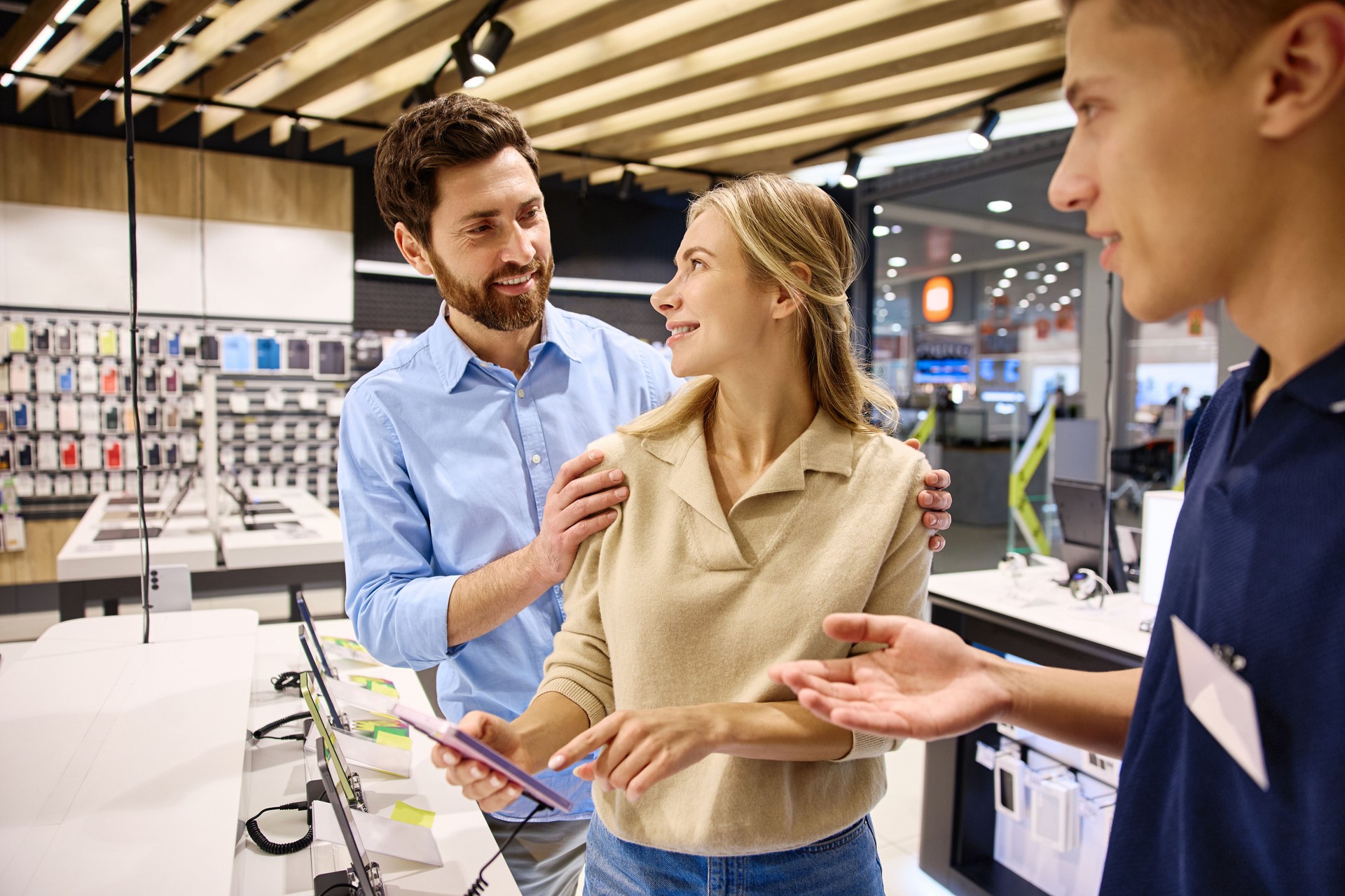 Exploring the shopping experience in a modern electronics store with customers and a salesperson