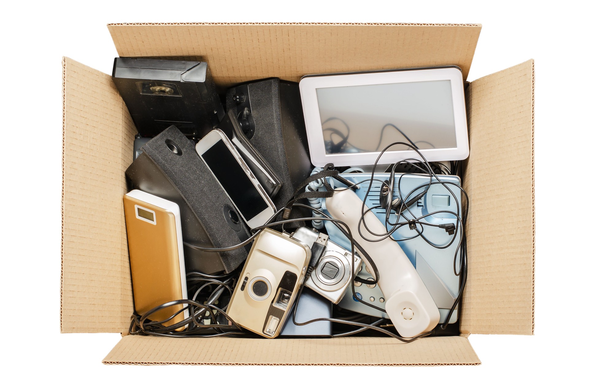 Old electronic devices in a cardboard box. The concept of recycling and disposal of electronic waste. Isolated on white
